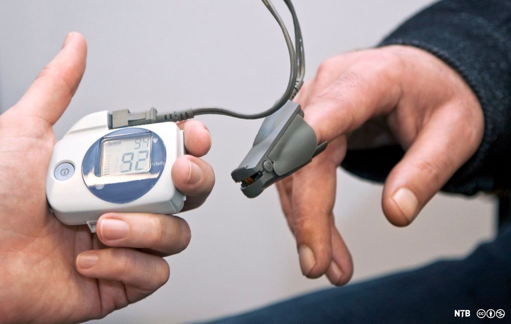 En klype koblet til et pulsoksymeter er festet til høyre pekefinger til en mann. Foto.