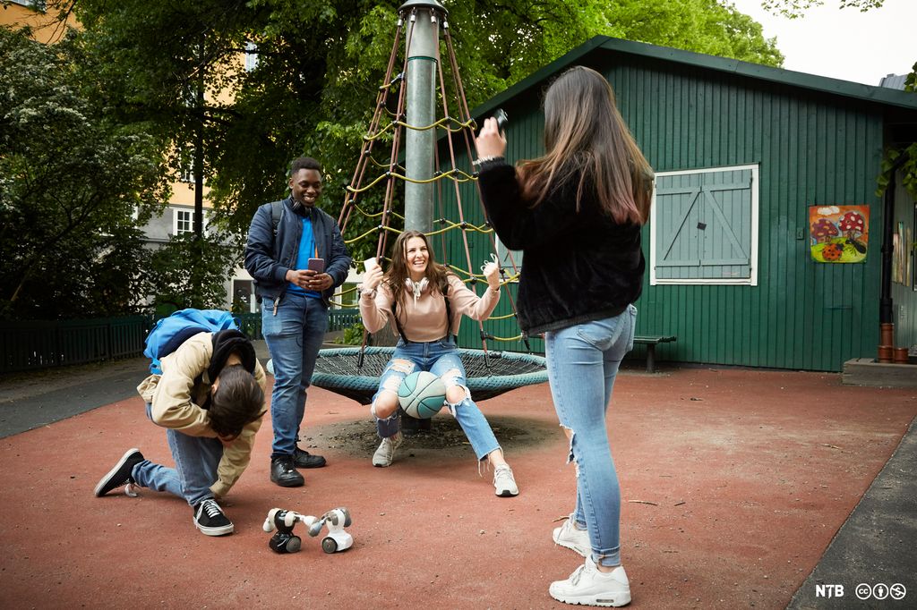 Fire ungdommer som leker med en robot på en lekeplass. Foto.