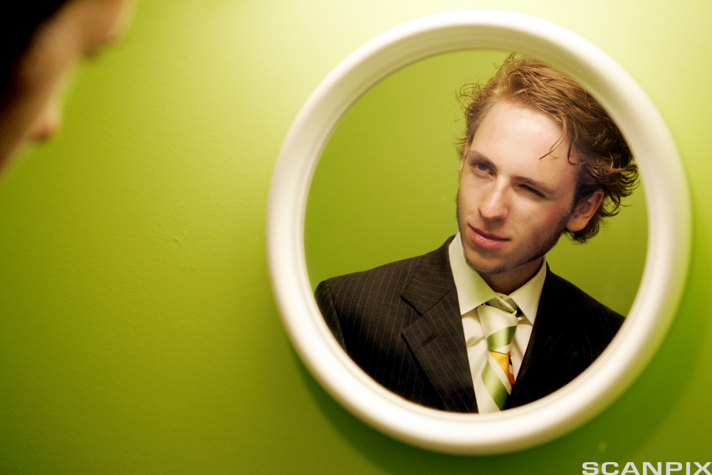 Ung mann ser seg selv i speilet. Foto. 