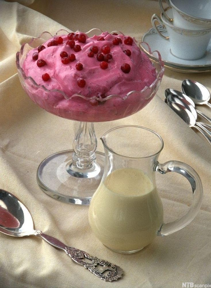 En skål med rosa krem pyntet med friske tyttebær. Foto.