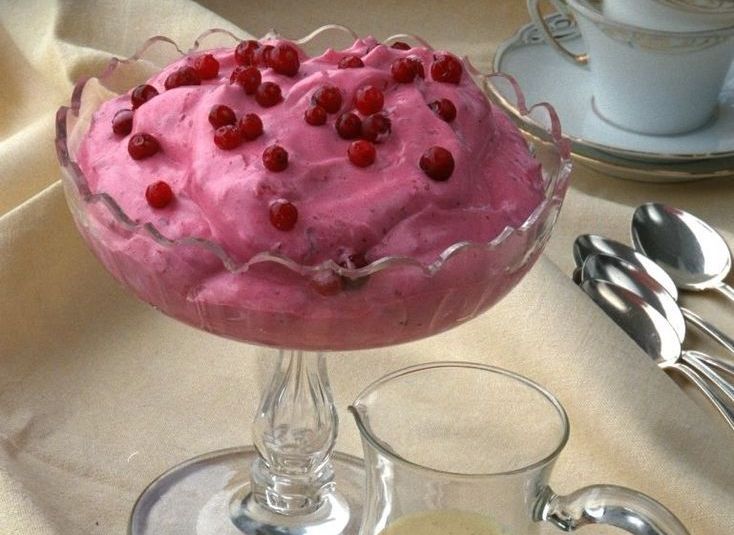 Ei skål med rosa krem pynta med friske tyttebær. Foto.