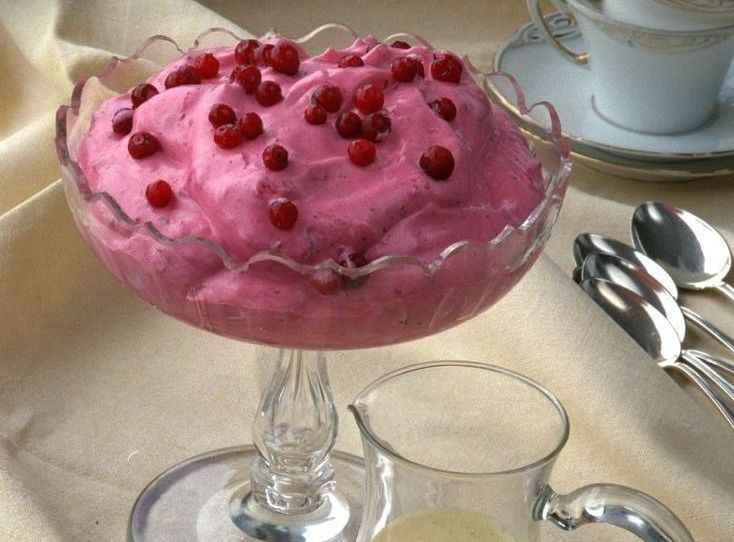 En skål med rosa krem pyntet med friske tyttebær. Foto.