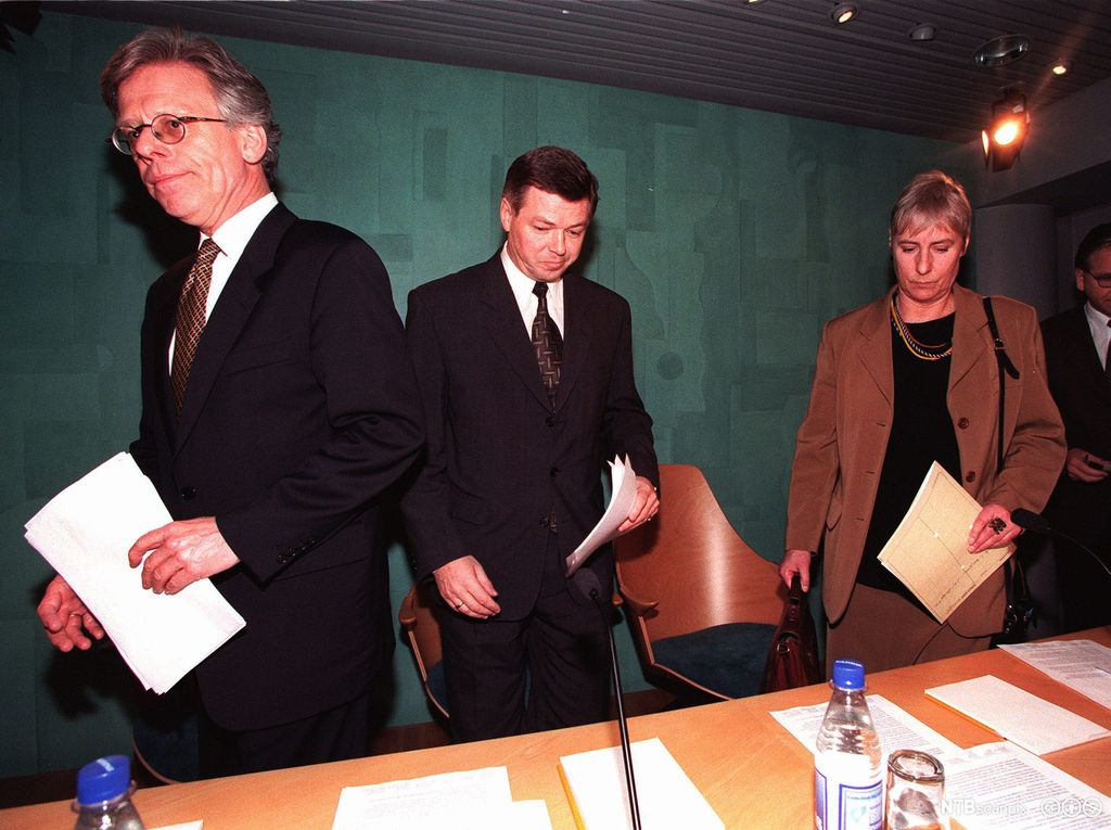 To menn og en kvinne reiser seg fra bordet etter å ha holdt en pressekonferanse. Foto.