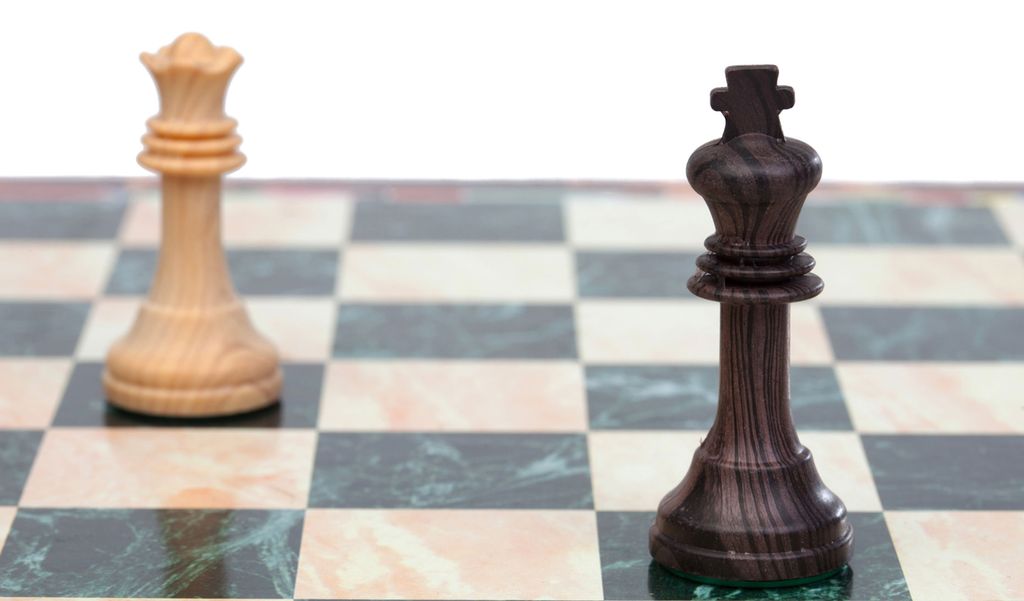 Sjakkbrett med svart konge og hvit dronning. Foto.