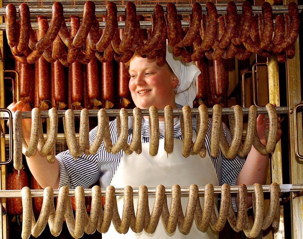 Pølsemaker henger opp pølser. Foto.