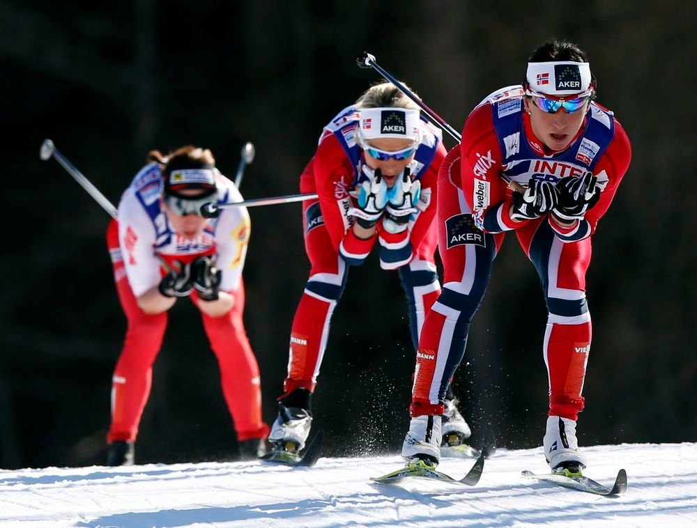 Tre skiløparar går i full fart, framoverbøygde med stavane bakover under armane. To av dei har norske fargar på trikoten. Foto frå ski-VM i Val di Fiemme 2013.