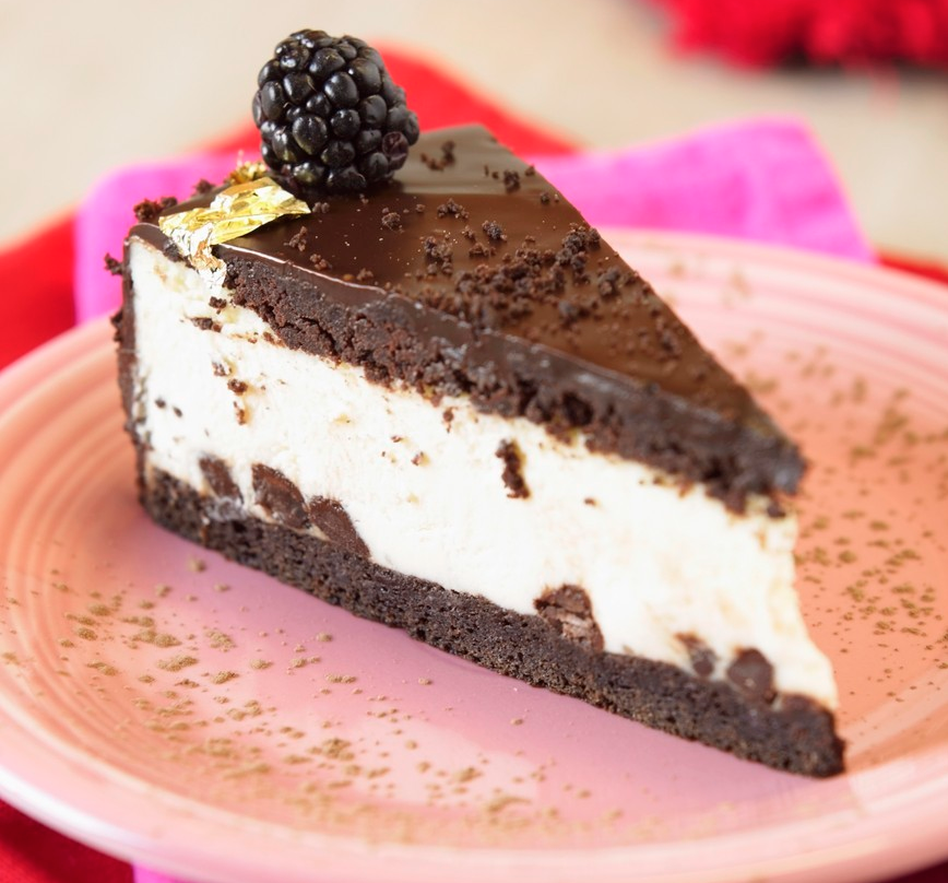 Eit stykke glutenfri sjokoladekake med kvitt fyll og bjørnebær til pynt. Foto.