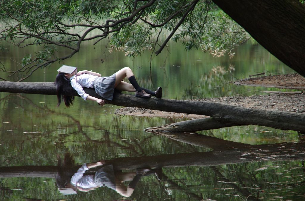 Jente sover med bok over ansiktet. Foto.
