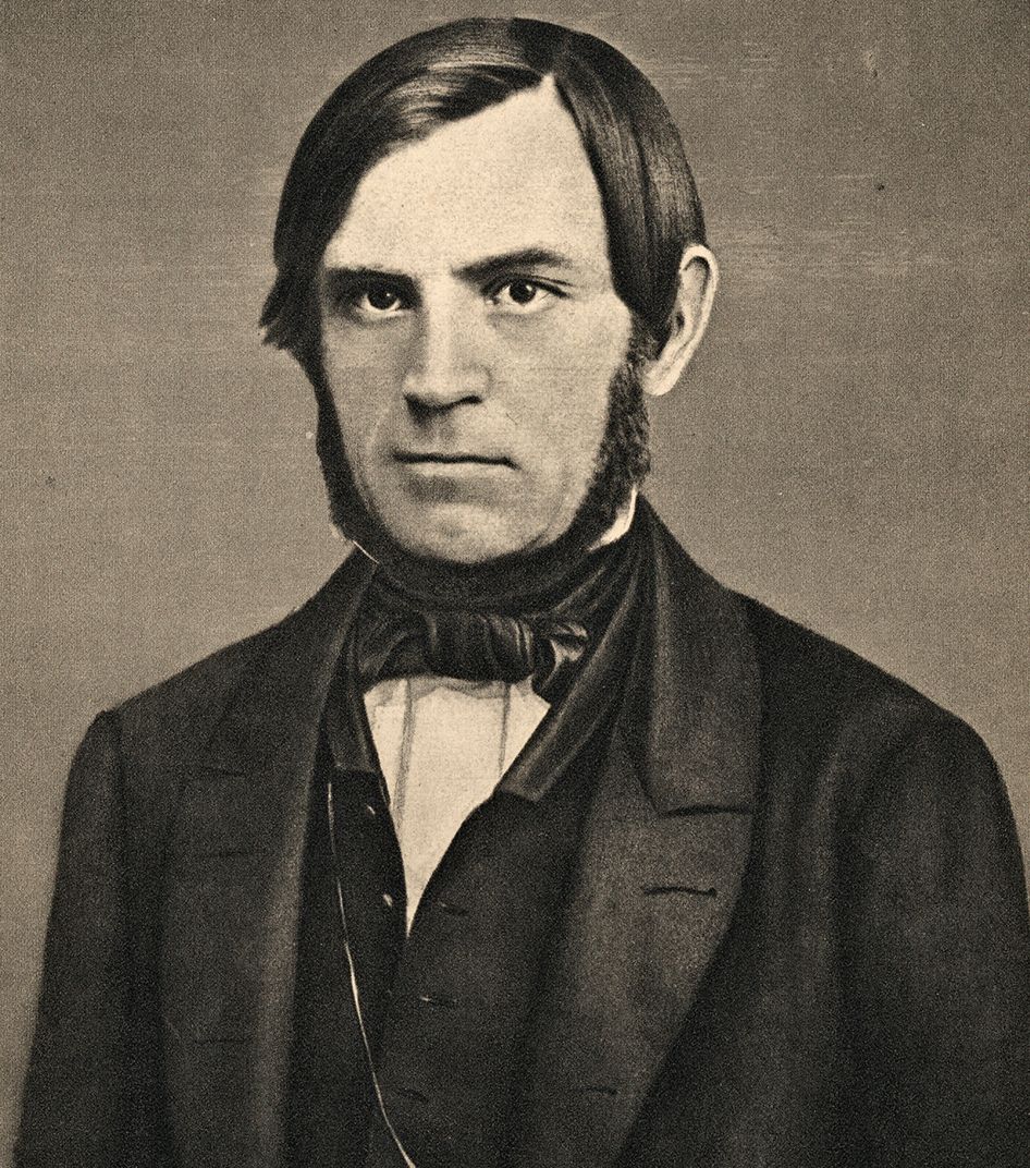 Portrett av Søren Jaabæk. Han har mørkt hår og er glattbarbert i ansiktet, men har skjegg i en krans fra foran ørene og inn under haka. Han er kledd i dress med vest og har tørkle i halsen. Foto.