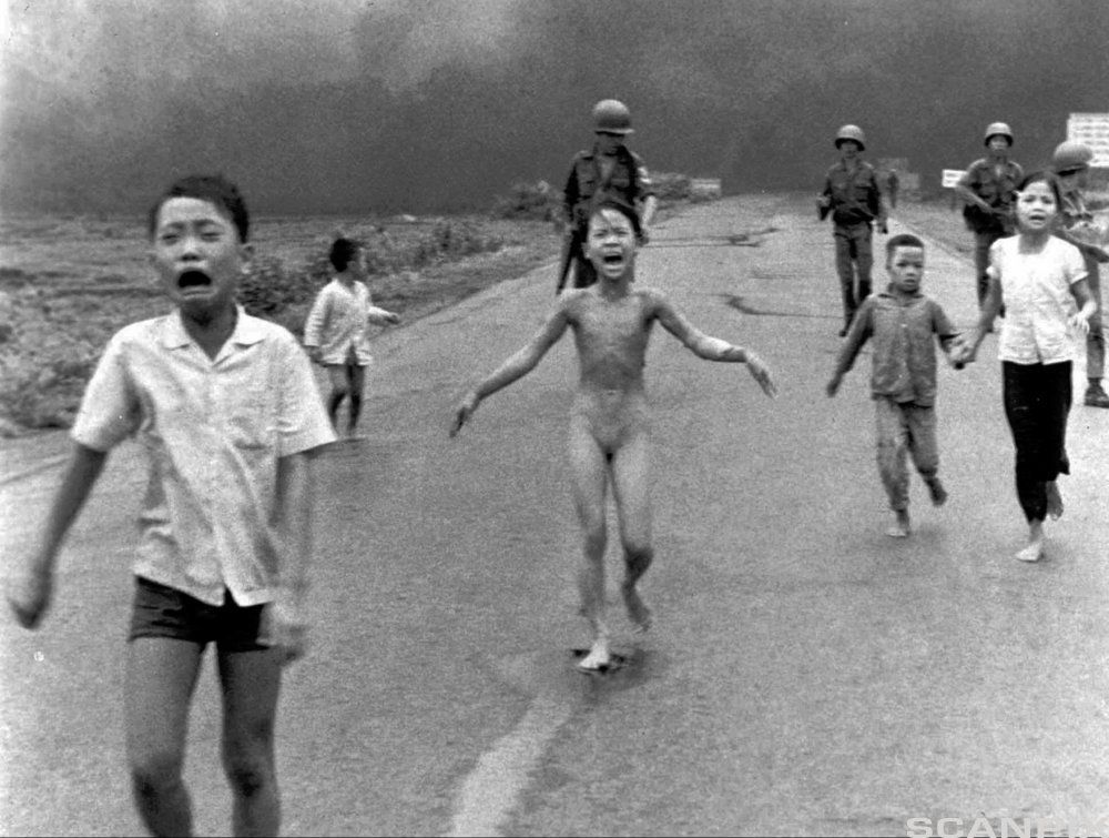Livredde barn flykter med soldater i bakgrunnen. Ei lita jente er helt naken etter å ha blitt angrepet med napalm. Foto.