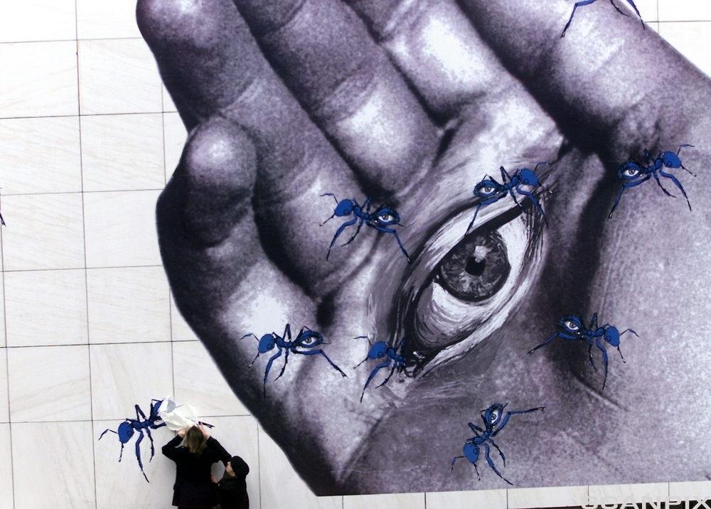 I en håndflate er det tegnet et åpent menneskeøye. I hånda kravler det maur med store menneskeøyne. Fotokollasj.