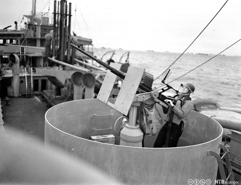 Mannskap ved luftskytskanonene på et skip. Svart-hvitt foto.