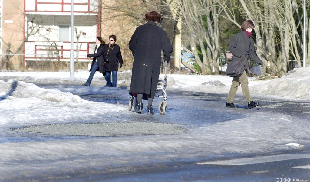 Eldre person som går med rullator på vinterføre. Foto.