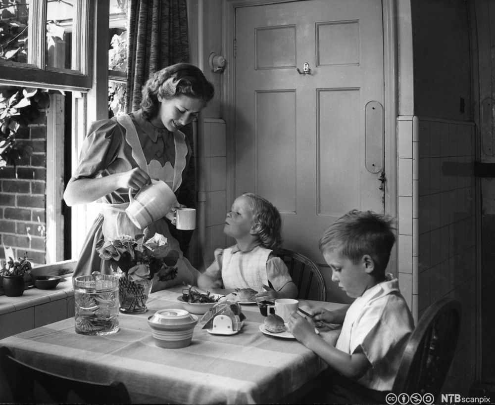Husmor som serverer frokost til to barn på 1950-tallet. Foto. 