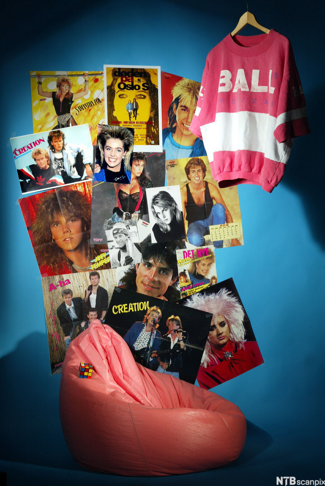 Rosa saccosekk under en vegg med plakater. Foto