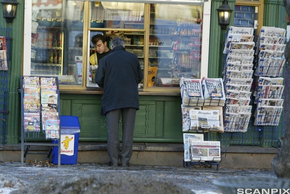 En kunde betaler for varer i et kioskvindu. Foto.