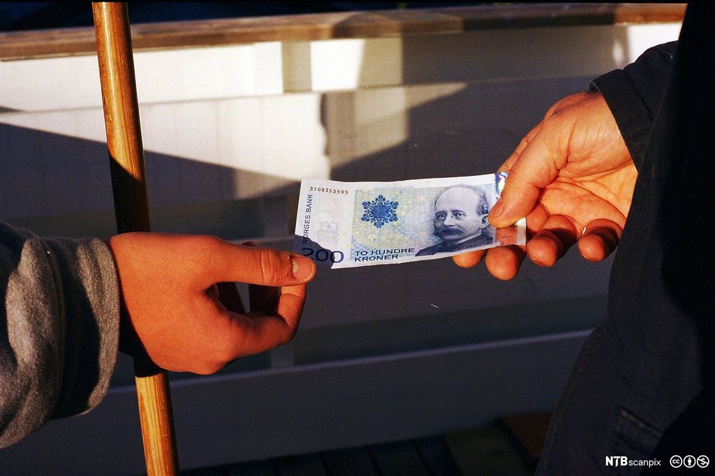 200-kroneseddel blir gitt fra en hånd til en annen. Foto.