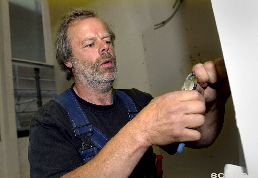 En montør på oppdrag kniper av en ledning. Foto.