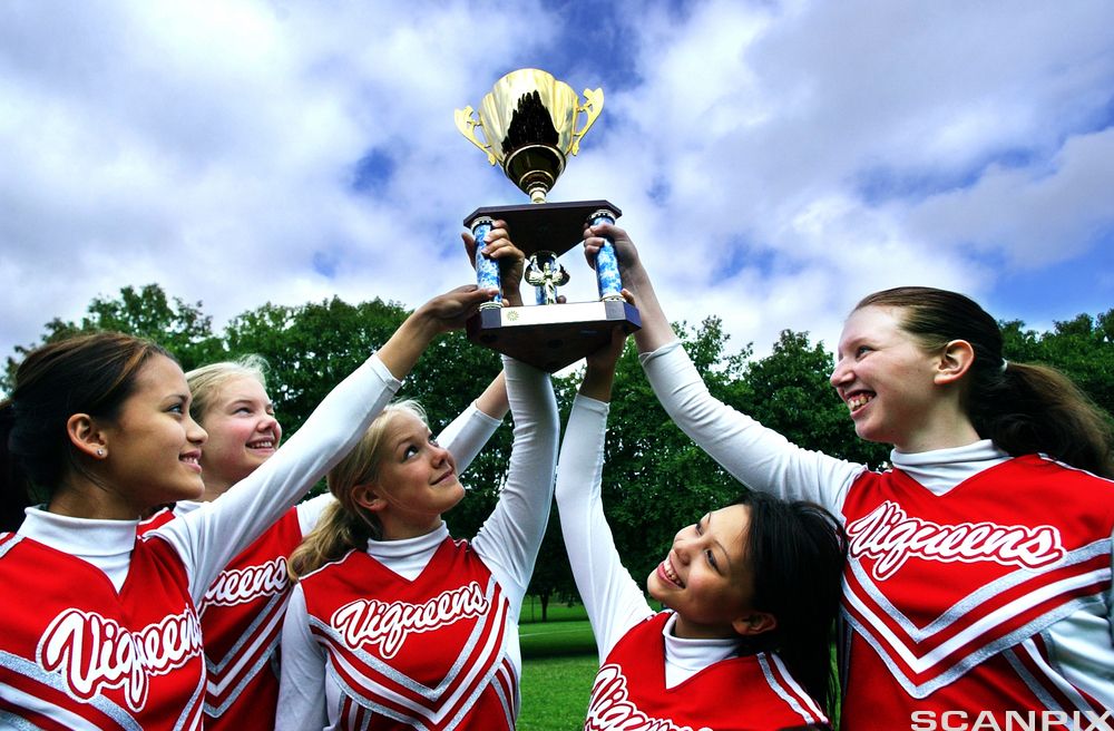 Fem jenter som holder en pokal. Foto.