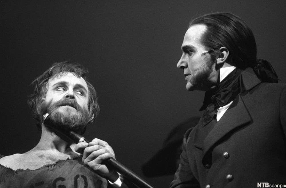 Helten i musikalen Les Miserables, Jean Valjean, og hovudmotstandaren hans, politimeister Javert. Javert  pressar skaftet av sabelen sin mot Jean Valjeans hals og truar han. Foto.
