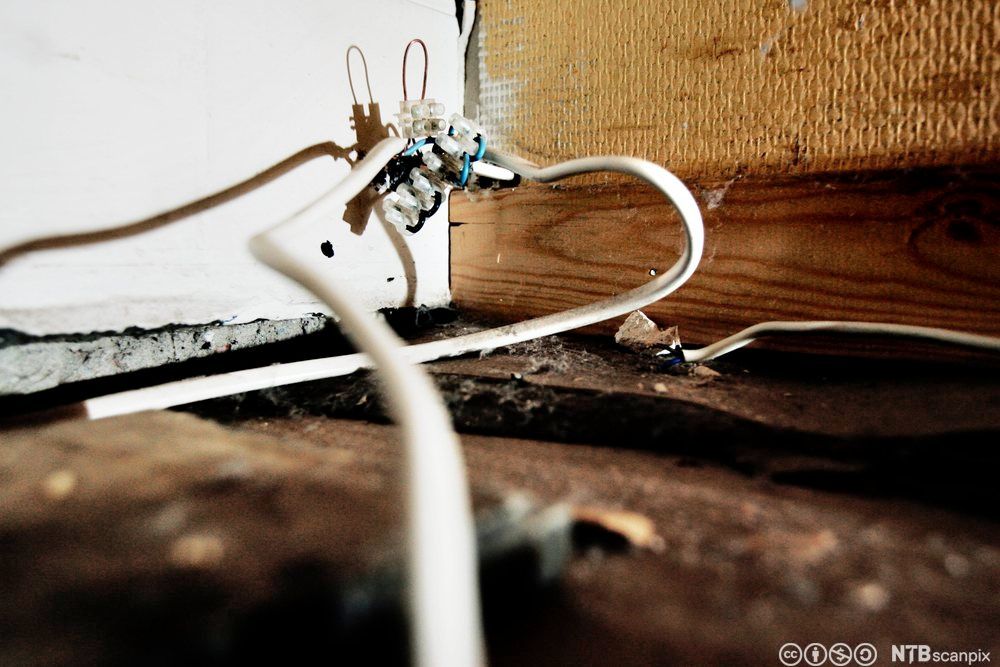 Nærbilete av eit hjørne i eit rom, der ein leidningsskøyt er heilt i det fri utan beskyttelse. Foto.