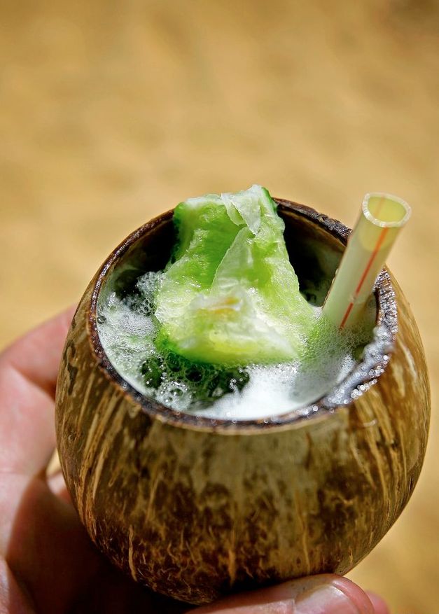 Kokosnøtt brukt som glass med caipirinha og sugerør oppi. Foto.