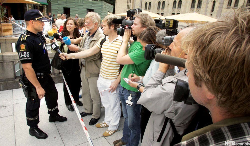 Politimann foran mange journalister og kamerafolk. Foto.