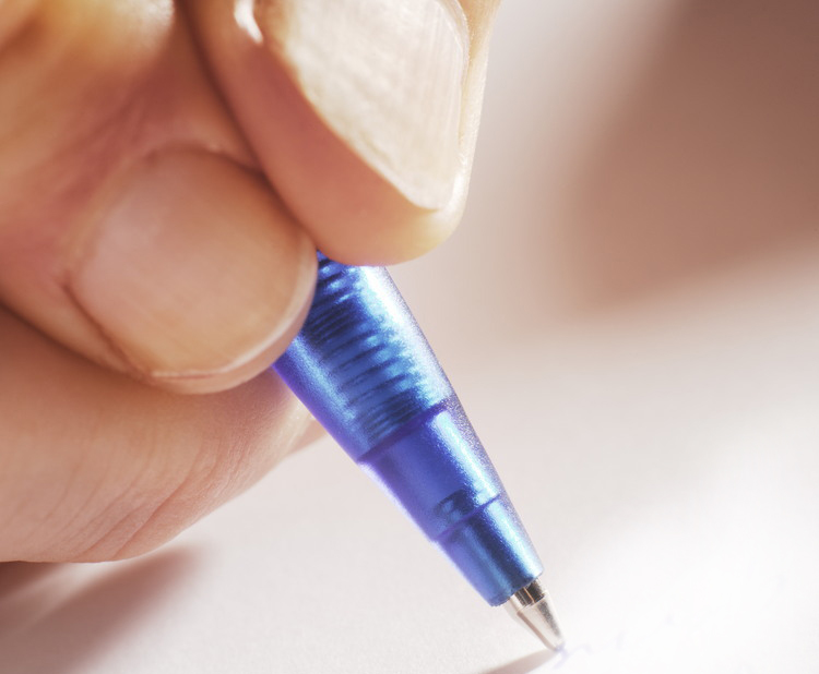 Hånd holder en kulepenn. Foto.