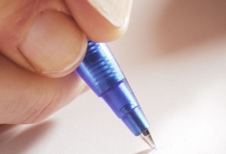 Hånd holder en kulepenn. Foto.