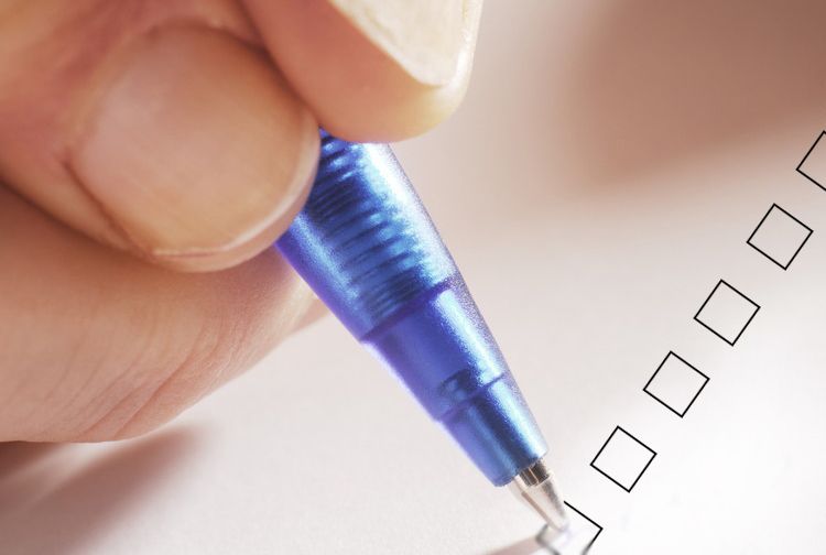 Hand held penn som skal fylle ut avmerkingsboks. Foto. 