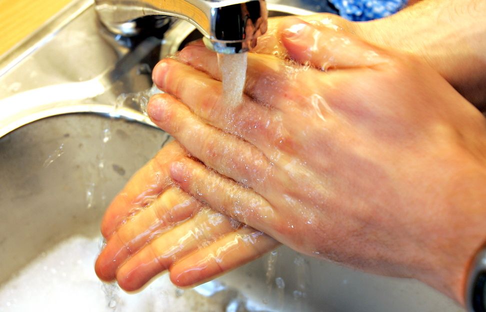 Et par hender under en rennende vask. Foto.
