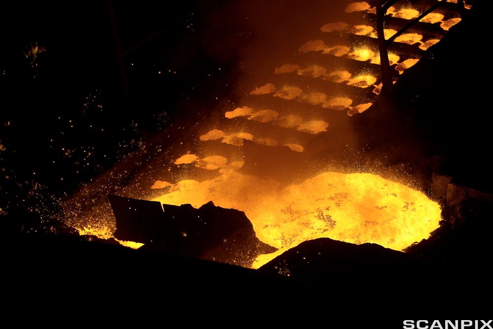 Ovn i smelteverk med glødende, smeltet metall. Foto.