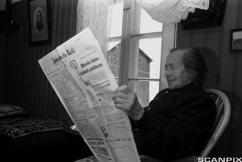 Kvinne som leser lokalavisa Arbeidets Rett. Svart-kvitt foto.