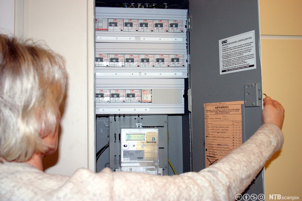 Voksen kvinne som åpner et sikringsskap. Foto.