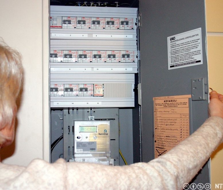 Voksen kvinne som åpner et sikringsskap. Foto.