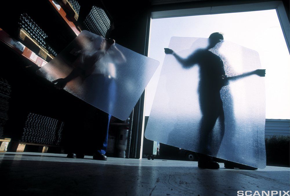 Mann legger plastunderlag til kontorstol. Foto.