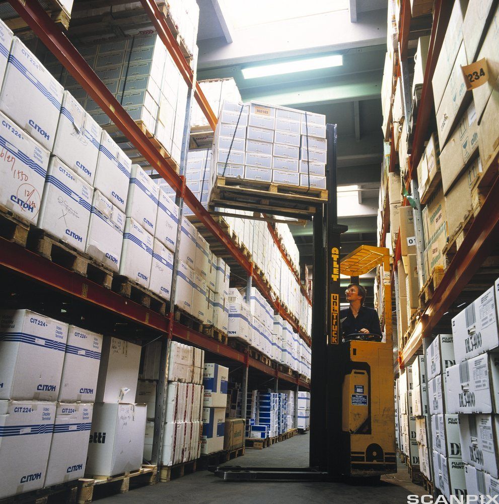 Gaffeltruck løfter paller inne på et lager. Foto.