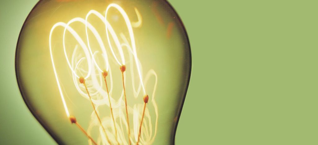 Nærbilde av en glødepære mot grønn bakgrunn. Foto.