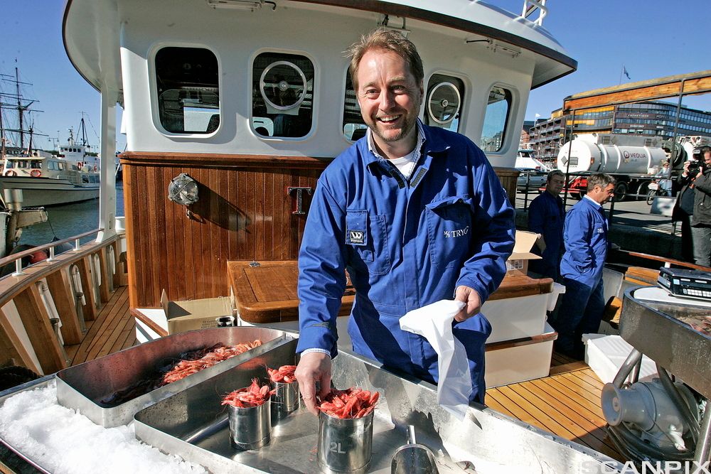 Investor Kjell Inge Røkke sel reker på ein fiskebåt ved kaia i Oslo. Foto.