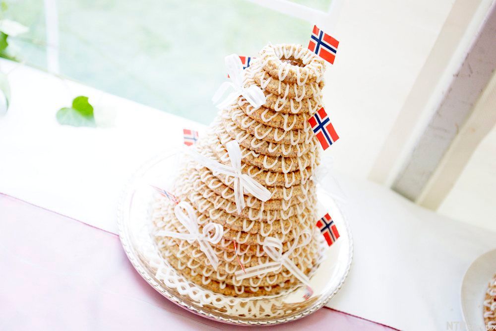 Festpyntet kransekake med hvite sløyfer og norske flagg. Foto.