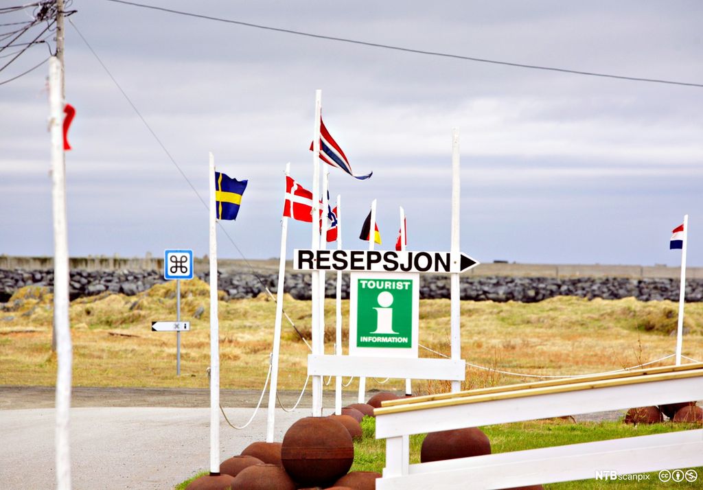 Internasjonale flagg og skilt med turistinformasjon i Berlevåg. Foto.