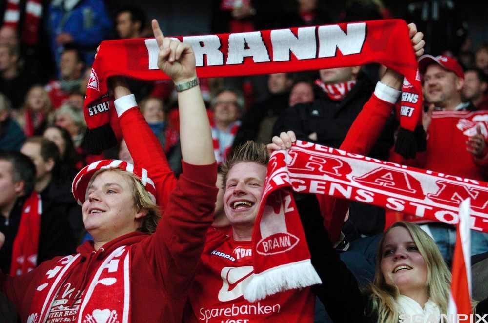 Brannsupportere som holder opp supporterskjerf på fotballkamp. Foto.