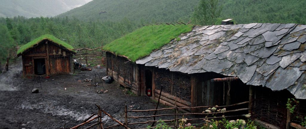 Gammelt gårdstun med skifer og gress på taket. Foto.