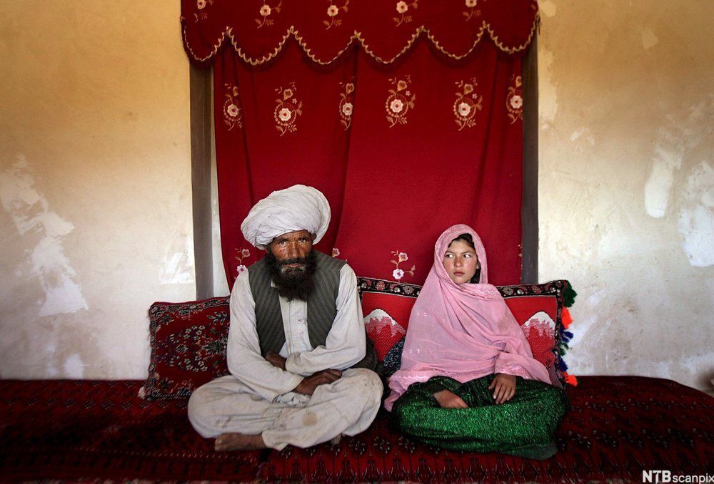 Tvangsbryllup i Afghanistan. En mann med turban og skjegg sitter ved siden av ei jente med rosa slør. (Bildet ble kåret til årets bilde av UNICEF i 2007.) Foto.