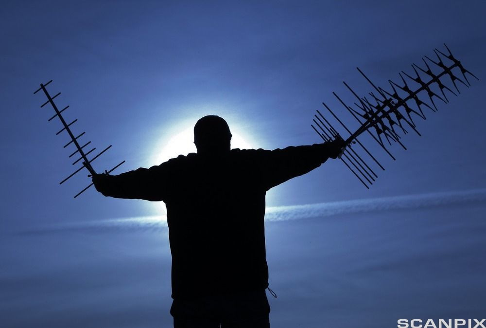 Silhuett av en mann som holder en antenne i hver hånd. Foto
