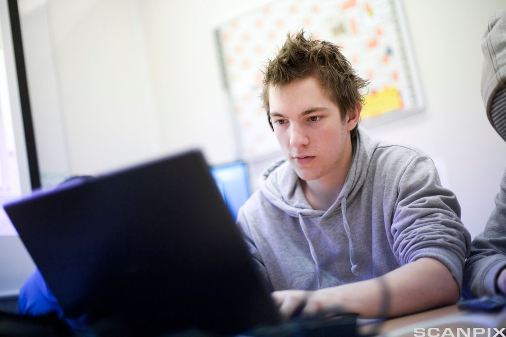 Gutt skriver på datamaskin. Foto. 
