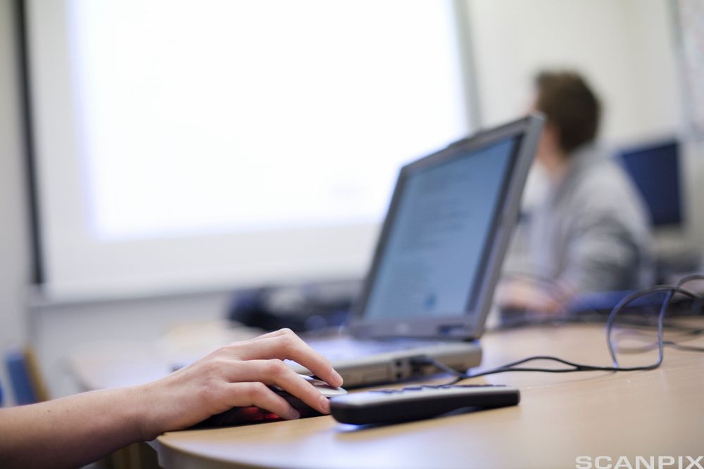 Nærbilde av hender som holder på med en bærbar datamaskin. Foto.