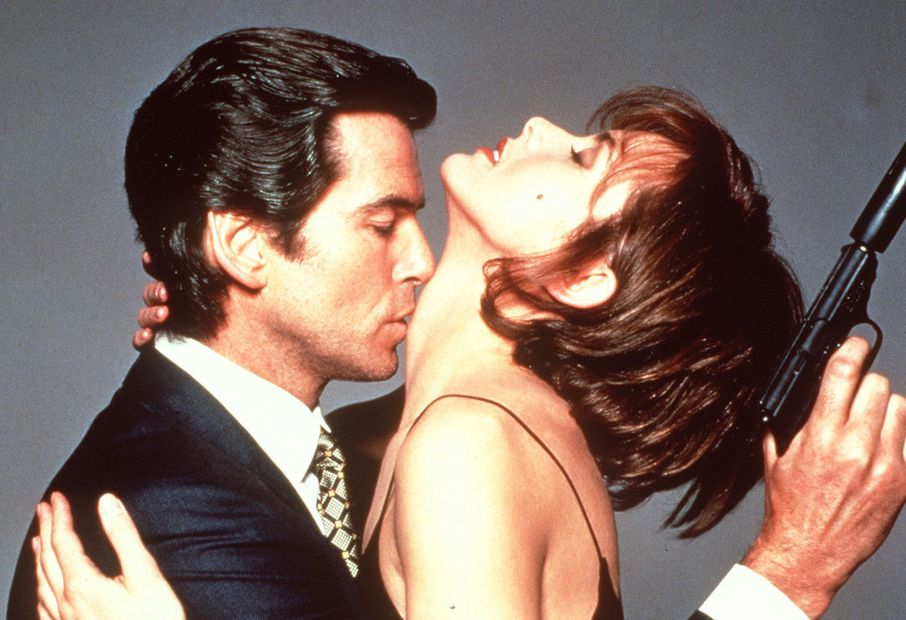 Mann med pistol kyssar kvinne på halsen. Foto.