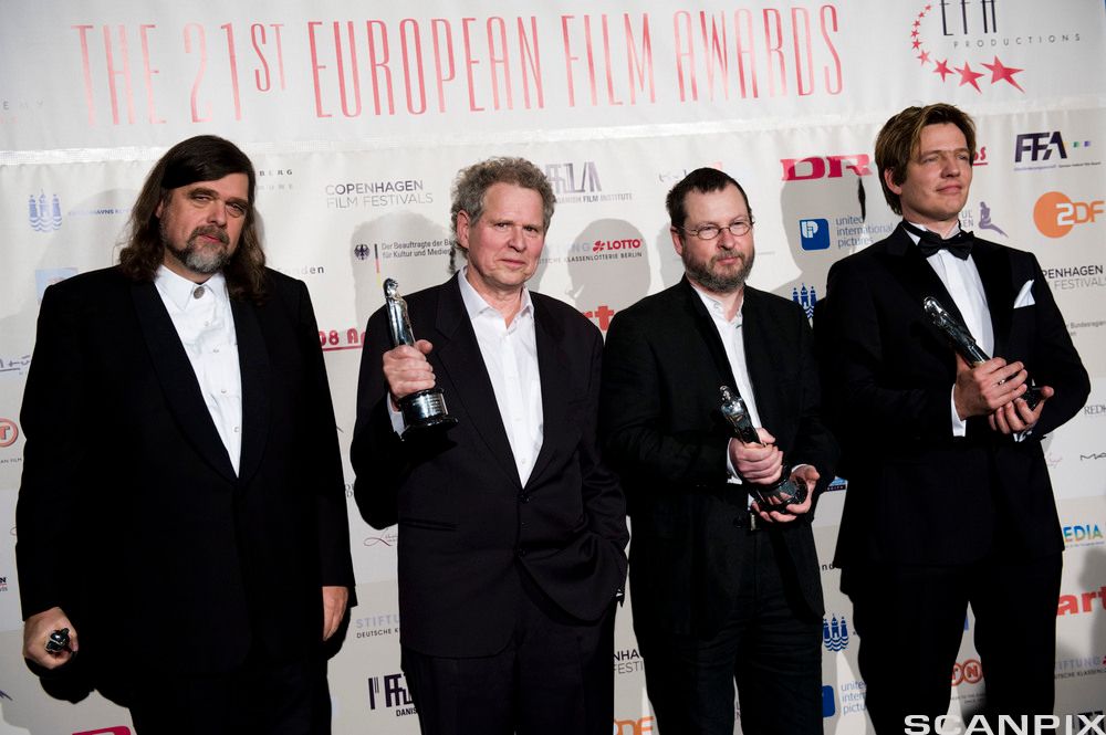 Fem menn i dress blir fotografert og holder hver sin filmstatuett. Foto.