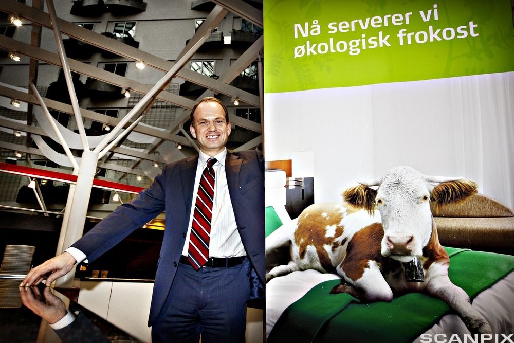 To bilder – ett av en smilende, dresskledd mann i spisesalen på et hotell, og ett av en reklameplakat med overskriften «Nå serverer vi økologisk frokost» og bilde av en ku som ligger i en hotellseng. Fotografier.